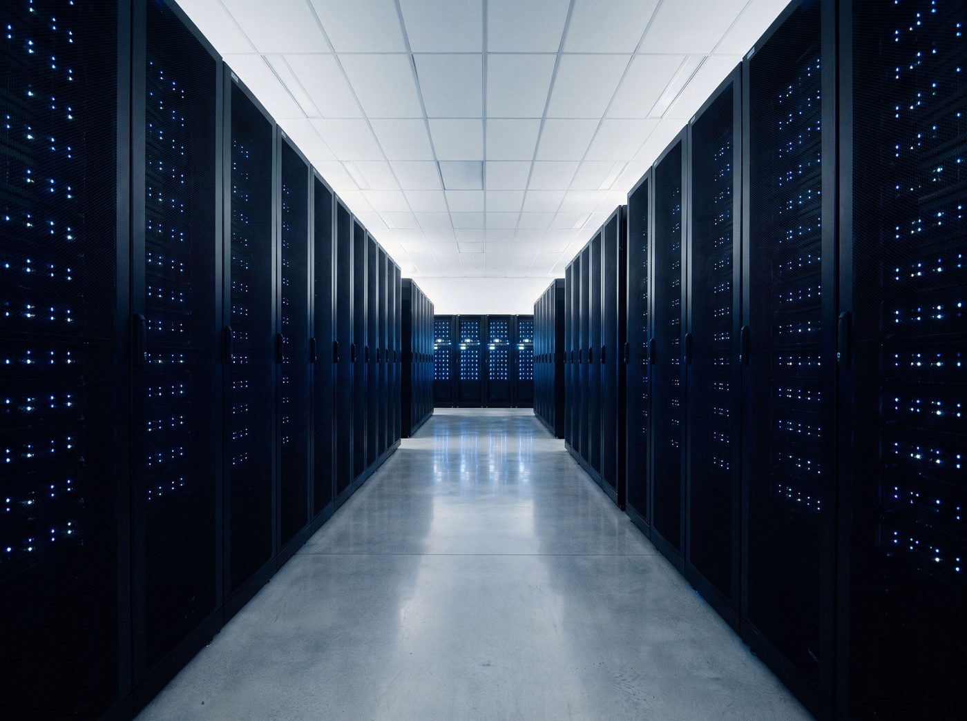 A clean data centre aisle lined with server racks and small blue status lights